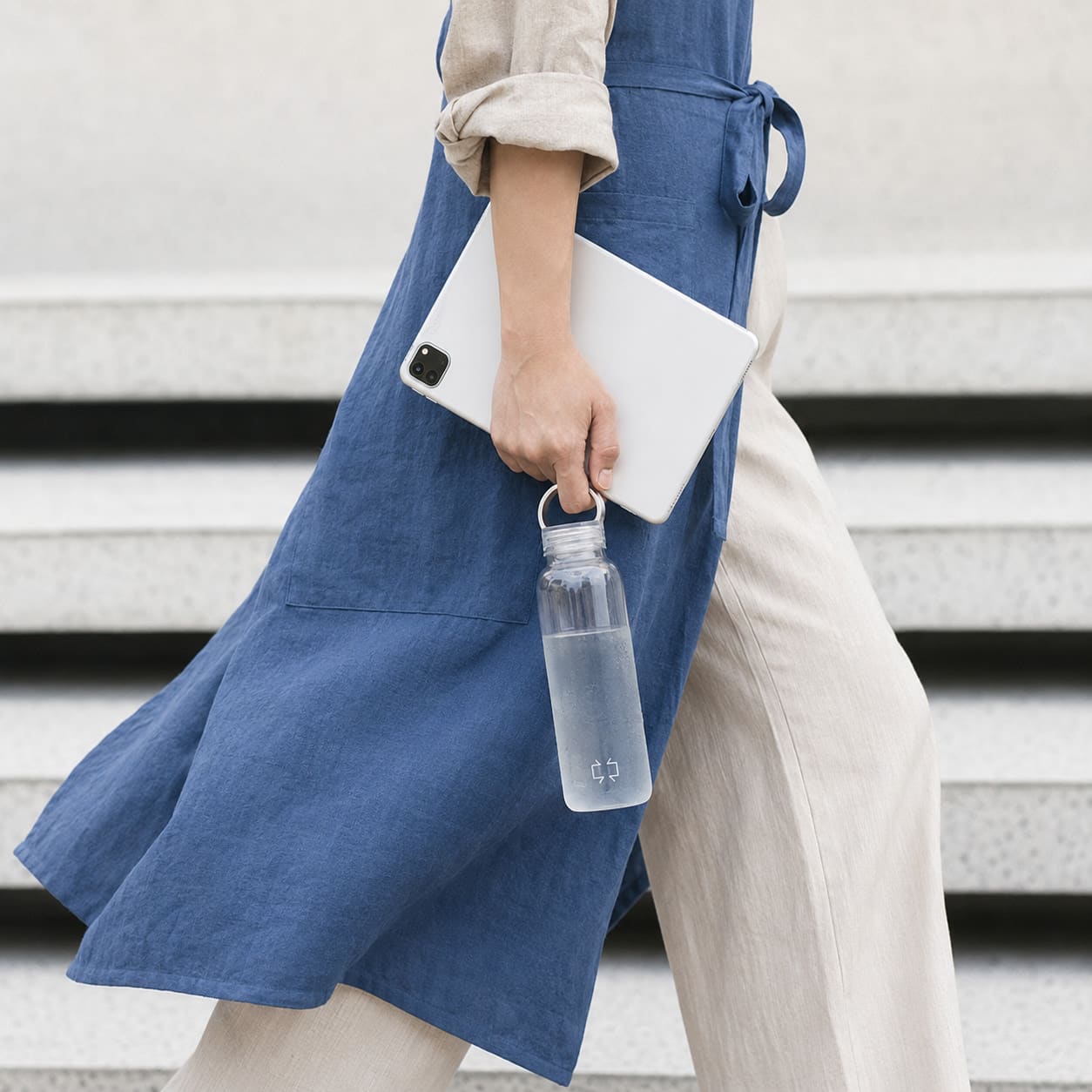 A water bottle marked with the bracket logo, carried with a tablet down stone steps.